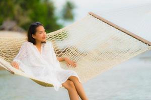 Portrait beautiful young asian woman sitting on hammock around sea beach ocean for relax photo