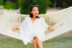 Portrait beautiful young asian woman sitting on hammock around sea beach ocean for relax photo