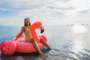 retrato, joven, mujer asiática, en, flotador inflable, flamingo, alrededor, piscina al aire libre, en, hotel, resort foto