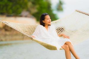 Portrait beautiful young asian woman sitting on hammock around sea beach ocean for relax photo