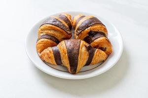 Fresh croissant with chocolate on plate