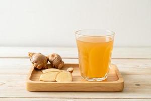 Fresh and hot ginger juice glass with ginger roots - Healthy drink style photo