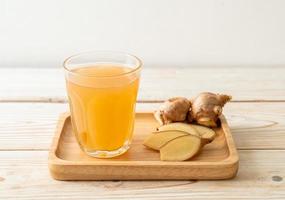 Fresh and hot ginger juice glass with ginger roots - Healthy drink style photo