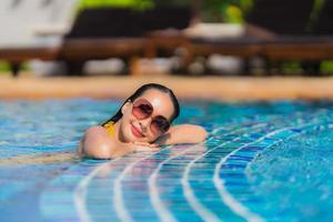 retrato, hermoso, joven, mujer asiática, ocio, relajarse, sonrisa, y, feliz, alrededor, piscina, en, hotel resort foto