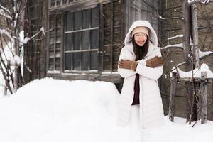 Hermosa joven asiática sonriendo feliz para viajar en la temporada de invierno con nieve