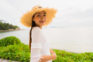 Retrato hermosa mujer asiática usar sombrero con sonrisa feliz ocio en la playa y el mar en vacaciones vacaciones foto