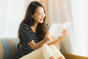 Portrait beautiful young asian woman reading book in on sofa in living room area photo