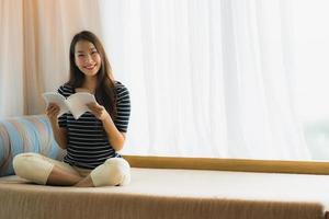 retrato, hermoso, joven, mujer asiática, libro de lectura, en, sofá, en, sala, área foto