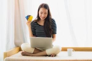 Portrait beautiful young asian woman using computer notebook or laptop with credit card for shopping photo