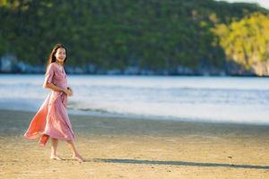 retrato, joven, hermoso, mujer asiática, caminar, sonrisa, y, feliz, en, el, playa, mar y océano foto