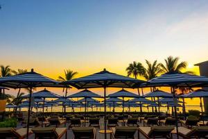 Umbrellas and chairs around outdoor swimming pool in hotel resort for holiday vacation travel background photo