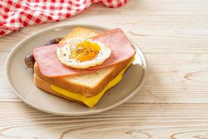 Homemade bread toasted cheese topped ham and fried egg with pork sausage for breakfast photo