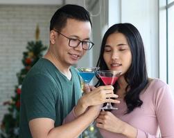 joven pareja asiática disfrutando de la navidad con champán foto