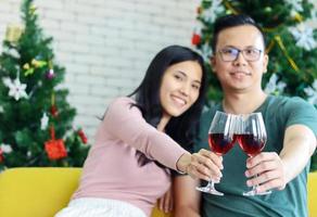 joven pareja asiática disfrutando de la navidad con champán foto