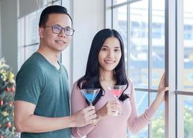joven pareja asiática disfrutando de la navidad con champán foto