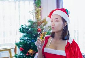 Asian woman wearing  Santa Claus hat. Celebrate Christmas by drinking champagne happily photo