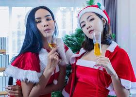 Mujer asiática vistiendo gorro de Papá Noel celebrar la Navidad bebiendo champán alegremente foto