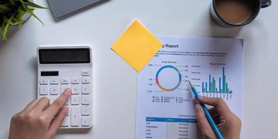 Woman with financial report and calculator. Woman using calculator to calculate report at the table in office photo