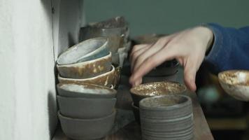 Close-up of hands organizing clay dishes on the shelves