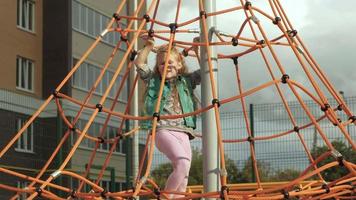A child climbs a rope horizontal bar in an outdoor playground video