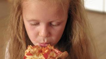 menina pré-escolar comendo pizza enquanto está sentada no chão da sala video