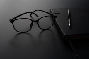 A picture of diary book of a student with eyeglasses on top on the black background photo