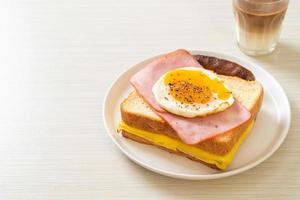 Homemade bread toasted cheese, topped ham, and fried egg with pork sausage for breakfast photo