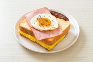 Homemade bread toasted cheese, topped ham, and fried egg with pork sausage for breakfast photo