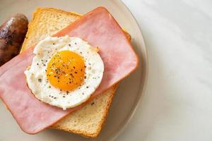 pan casero, queso tostado, jamón cubierto y huevo frito con salchicha de cerdo para el desayuno foto