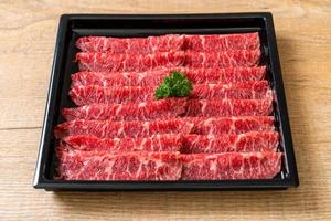Carne fresca cruda en rodajas con textura de mármol servida para sukiyaki y shabu o yakiniku