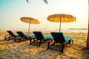 Umbrella beach chair with palm tree and sea beach at sunrise time - vacation and holiday concept photo