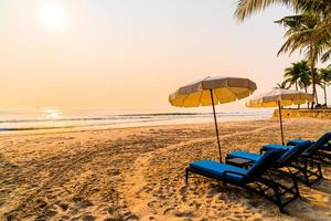 Umbrella beach chair with palm tree and sea beach at sunrise time - vacation and holiday concept photo