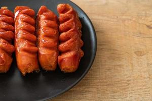 Deep-fried sausage skewer on black plate photo