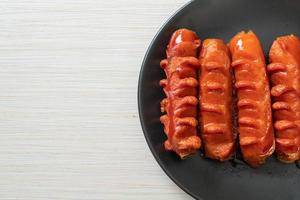 Deep-fried sausage skewer on black plate photo