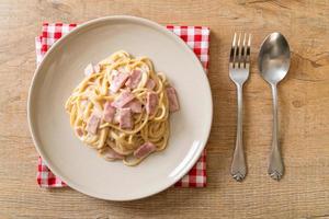 Espaguetis caseros con salsa de crema blanca con jamón - estilo de comida italiana foto