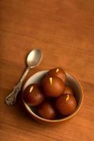 Gulab Jamun in bowl on wooden background. Indian Dessert or Sweet Dish. photo