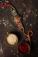 Raksha Bandhan background with an elegant Rakhi, Rice Grains and Kumkum. A traditional Indian wrist band which is a symbol of love between Brothers and Sisters. photo