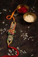 Raksha Bandhan background with an elegant Rakhi, Rice Grains and Kumkum. A traditional Indian wrist band which is a symbol of love between Brothers and Sisters. photo