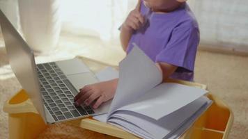 niño asiático usando una computadora portátil estudiar lección en línea en casa. educación en el hogar aprendizaje a distancia, distancia social durante la cuarentena de covid-19, no ir a la escuela, concepto de educación remota de educación en el hogar cámara lenta video