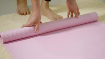 mujer joven asiática rodante fitness yoga mat rosa después de la práctica deportiva para hacer ejercicio, mujer trabajando en casa en la sala de estar. concepto saludable de estilo de vida deportivo, cámara lenta de 60 fps video