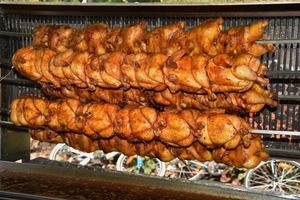 Pollos asados en asador a la parrilla sobre el fuego de una gran barbacoa foto