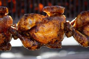 Roasted chickens on spit grilled over fire of a big barbecue photo