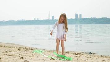 una niña en edad preescolar con una cinta de gimnasia en una playa de arena