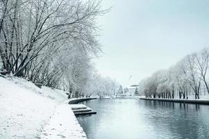 invierno en la ciudad - nieve en las orillas del río y en los árboles cubiertos de escarcha foto
