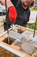 Hands of a professional bricklayer while working on a construction site - masonry wall from a concrete block photo