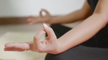 polainas de mujer joven asiática practicando yoga en casa sentado en posición de loto en la estera de yoga para el equilibrio, mujer trabajando en casa en la sala de estar. estilo de vida deporte concepto de meditación saludable, cámara lenta video