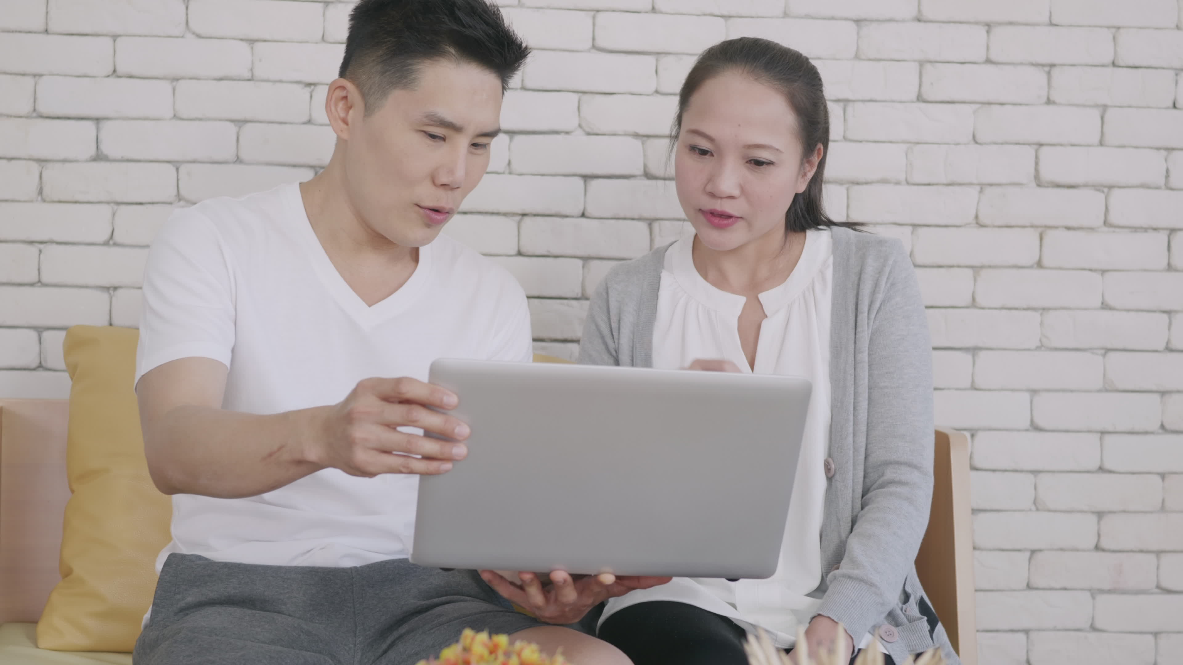 Happy Asian family couple husband and wife work and using laptop computer analyzing their finances discuss