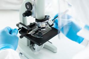 Close up picture of scientist wearing personal protective equipment or ppe using microscope to do experiment about covid-19 or coronavirus vaccine in the lab. science and medical concept photo