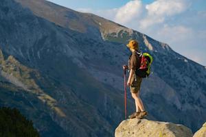 Young woman traveler with backpack in the mountains photo