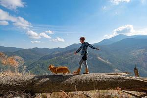 Young woman traveler with corgi dog in the mountains photo